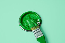 Green Paint In A Paintbrush And Lid Of A Paint Can