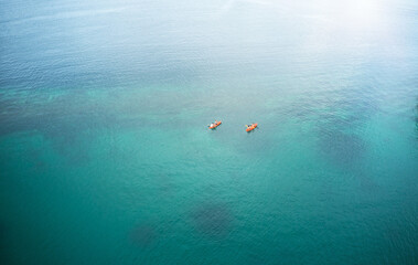 Wall Mural - Exploring the beauty of the ocean one paddle at a time. High angle shot of two adventurous young couples canoeing together in the beautiful oceans of Indonesia.