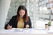 © Wasan - Business woman in the office working with financial data using calculator and writing make notepad. Business financial and accounting concept.