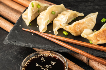 Sticker - Chinese cuisine gyoza dumplings on dark slate stone.