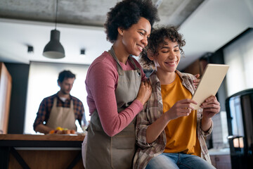 Wall Mural - African american mother and teenage girl using digital tablet and having fun together at home