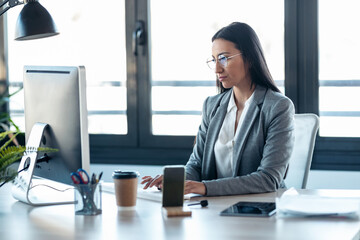 Concentrated young business woman working with computer in the office.