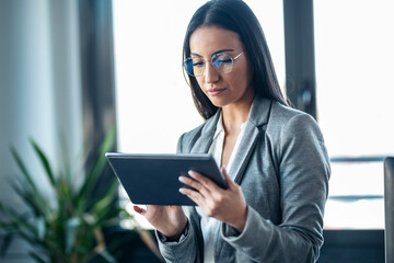 beauty business woman using her digital tablet while sitting on a desk in a modern startup office.