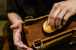 © Vipada - Professional leather care service concept. Closeup hand with yellow soft sponge cleaning surface of the vintage brown bag, depth of field. Polish waxing protection from dust and dirt.