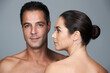 © Nicola Katie/peopleimages.com - Body conscious couple. Studio portrait of a mature couple standing close together against a gray background.