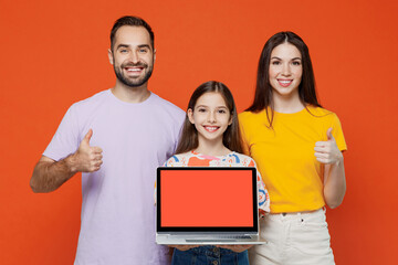 Wall Mural - Young parents mom dad with child kid daughter teen girl in basic t-shirt hold use work on laptop pc computer blank screen workspace area show thumb up isolated on yellow background Family day concept