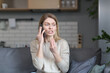 © Liubomir - Annoyed woman at home sitting on the couch and talking on the phone