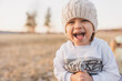 little boy smile and scream in knitted hat in sunlight, portrait of happy child outdoors walk in field