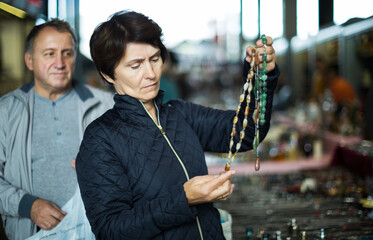 Wall Mural - Adult cheeful man and his wife are visiting market of old things and looking collectible outdoors.