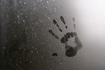 vidrio de ventana empañado por lluvia afuera con manos marcadas en el interior