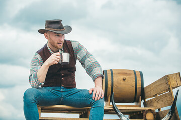 Portrait of farmer or cowboy holding cup coffee or tea outdoor.