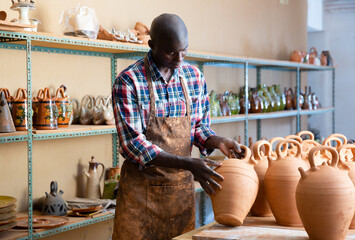 Wall Mural - Afro-american artisan in apron having ceramics in store warehouse