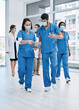 © Nicholas Felix/peopleimages.com - They communicate often and share resources where needed. Shot of two medical practitioners going through notes while walking in a busy hospital.