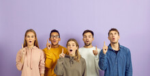 Group Of Happy Young Diverse Multiethnic People Surprised By Bright Idea And Solution Standing On Purple Color Background And Pointing Index Fingers Up With Open Mouths And Surprised Face Expressions