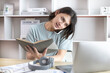 © Puwasit Inyavileart - Asian male worker talking on phone and working on laptop with smiling face, Office staff work and telephone conversations, Take notes for reminders, Business conversation over the phone.