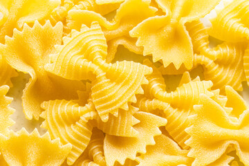 Wall Mural - food background from uncooked farfalle pasta pieces close up