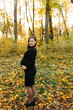 © Anhelina  - Beautiful pregnant woman in a black dress in the autumn park. Golden autumn. Fallen leaves. Awaiting the birth of a child.