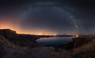 Sticker - Beautiful shot of a pond surrounded by cliffs in the background of a starry sky.