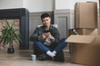 © ReeldealHD images - Mid adult male sitting on the floor in new home using smartphone surrounded by boxes