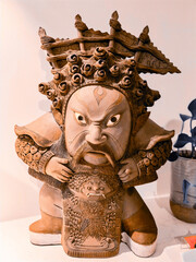 Poster - Close-up shot of a clay statue of a small Asian man which can be a statue of an Asian deity