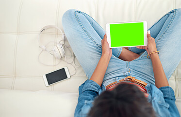 Wall Mural - Enjoying a no-stress day at home. High angle shot of a young woman using her digital tablet while sitting on the sofa.