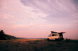 Mobile home in the middle of the countryside. With tent on top. Camping car, van, camper, motor home. Sunset with purple, lilac tones. Natural background, mountain.