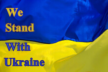 We stand with Ukraine - inscription on background of Ukrainian flag. Support and assistance to Ukraine in fight against Russian war and aggression