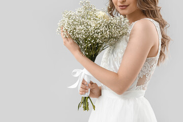 Wall Mural - Beautiful bride with bouquet of flowers on light background