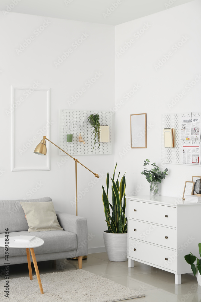 Interior of light living room with sofa and hanging peg boards