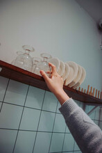 Girl's Hand Putting A Glass Cup On A Wooden Dish Drying Rack