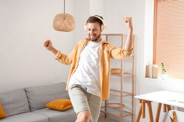Wall Mural - Young man in headphones dancing at home