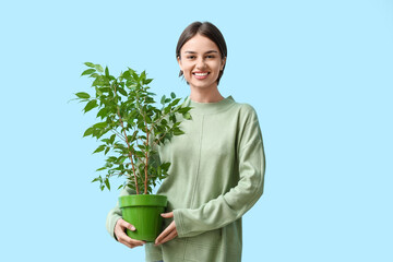 Beautiful young woman with houseplant on color background