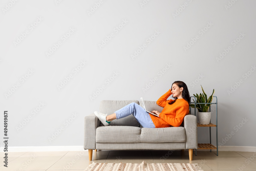 Beautiful young woman with laptop resting on couch at home Stock Photo ...