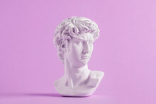 Ancient Statue Is Head Of David On Purple Background.