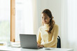 © PaeGAG - Charming asian businesswoman sitting working on laptop in office.