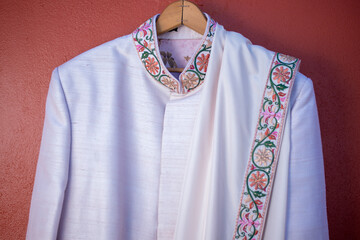 Wall Mural - Closeup of a traditional wedding outfit for a groom hanging from a wooden hanger