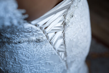 Closeup of the back of a bride's dress with ties surrounded by lace details