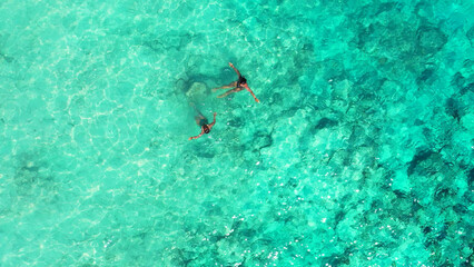 Aerial top view of two girls swimming in the ocean in Gili Meno, Lombok, Indonesia
