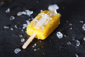 Poster - Closeup of a mango ice cream with melting ice on a black table