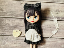 Cute Girl Doll In A Maid Costume On A Wooden Table