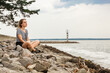 © Minakryn Ruslan  - Beautiful girl on the sea overlooking the lighthouse and blue sky with clouds