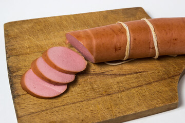 Wall Mural - Boiled sausage on a white background. Sliced sausage stick on a wooden board. Sausage product.