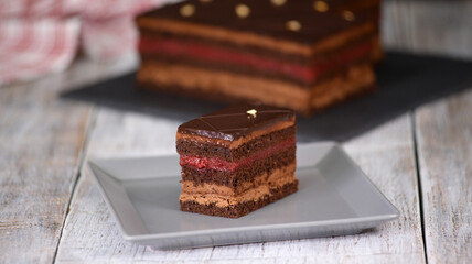 Wall Mural - Sponge cake slice with chocolate mousse, jellied cherry jam topped with chocolate icing.