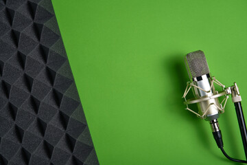 Wall Mural - Microphone on green background with copy space and acoustic foam panel