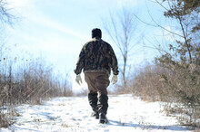 Adult Man Wearing A Thick Coat With Gloves And Walking In A Field Covered In The Snow