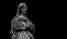 Virgin Mary. An Ancient Statue Isolated On Black Background. Copy Space For Design.