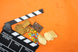 clapper board of video cinema in studio.Movie production clapper board and chocolate candy and bars with chips and biscuit on orange background