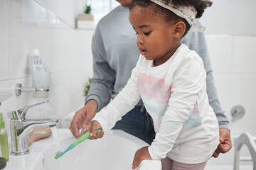 Wall Mural - Learning all about good hygiene from a young age. Shot of a mother helping her little daughter rinse her toothbrush at a tap in the bathroom at home.