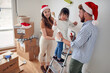 © luckybusiness - little girl standing on ladder between parents in new apartment, playing to paint the wall. young family in new apartment with christmas hats