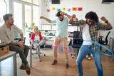 Fototapeta Na sufit - A group of employees is having fun while playing with hula-hoop in the office. Employees, job, office